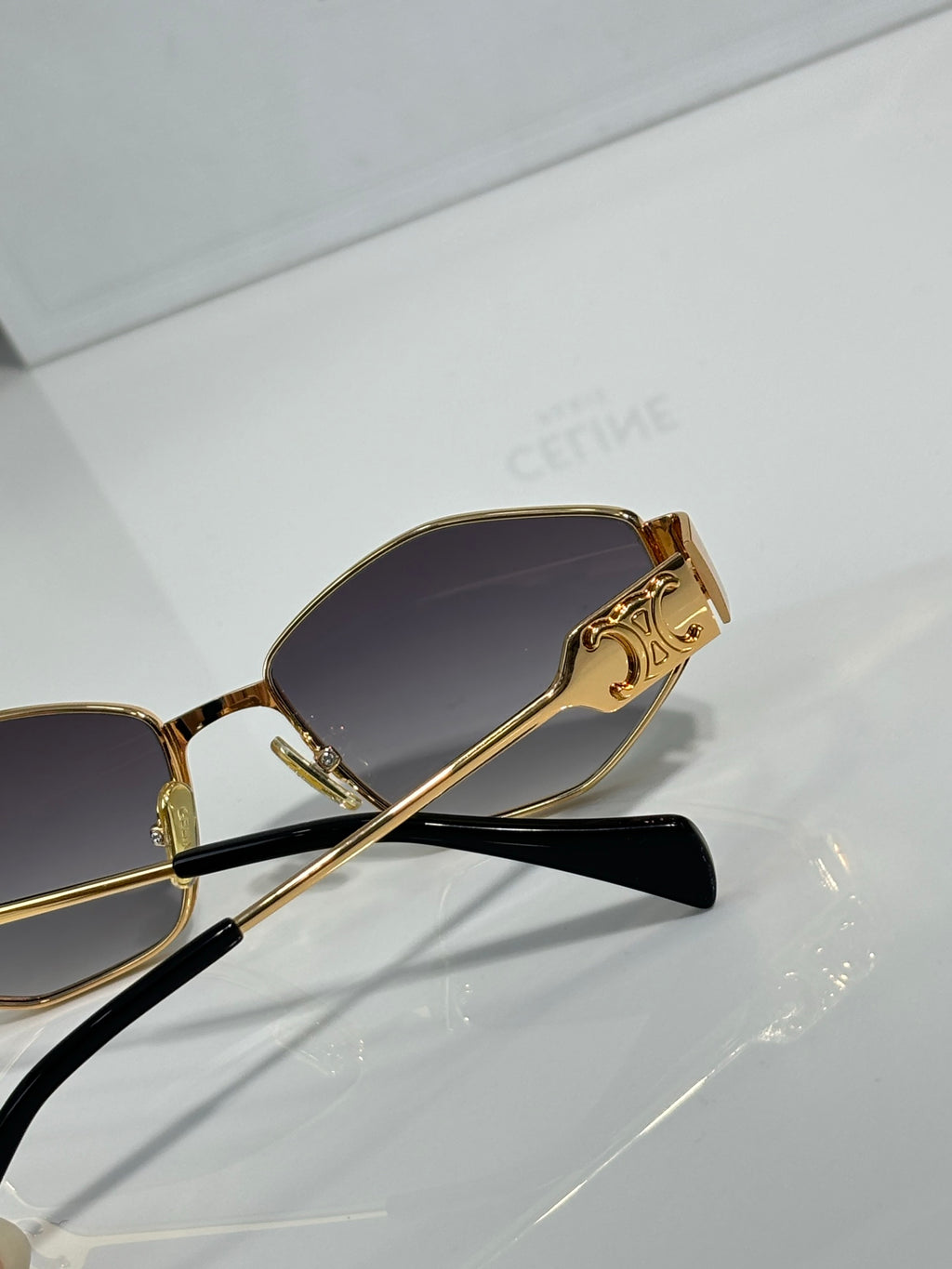 Gold temple detail sunglasses with dark tinted lenses, close-up angle