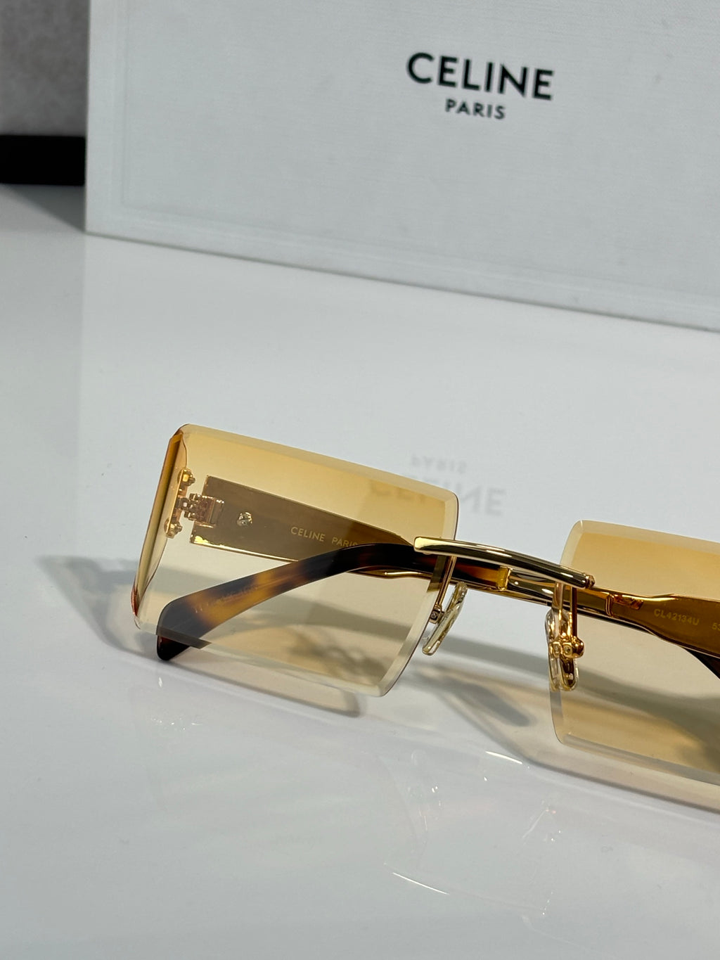 Celine sunglasses close-up with amber rectangular lenses and gold frame with engraved details