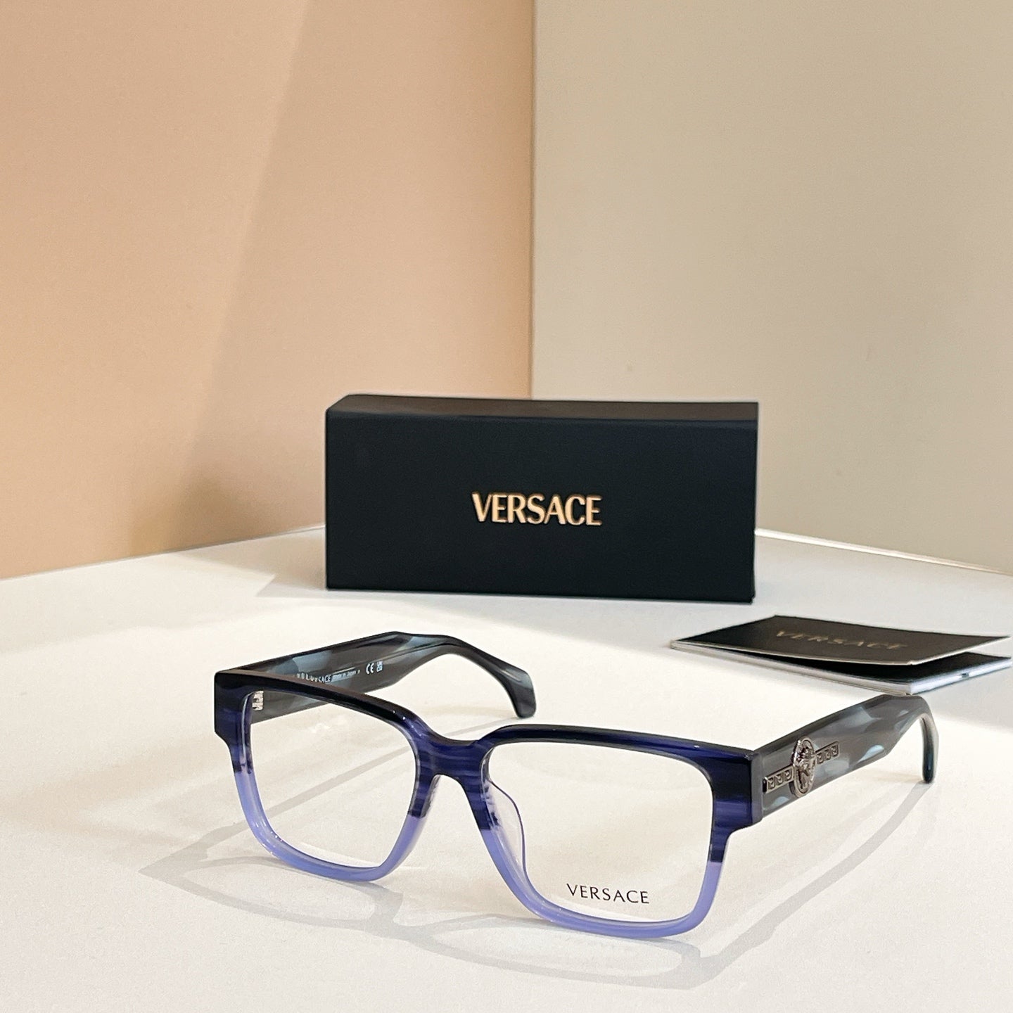 Versace glasses with blue square frames and gold emblem on temple arms