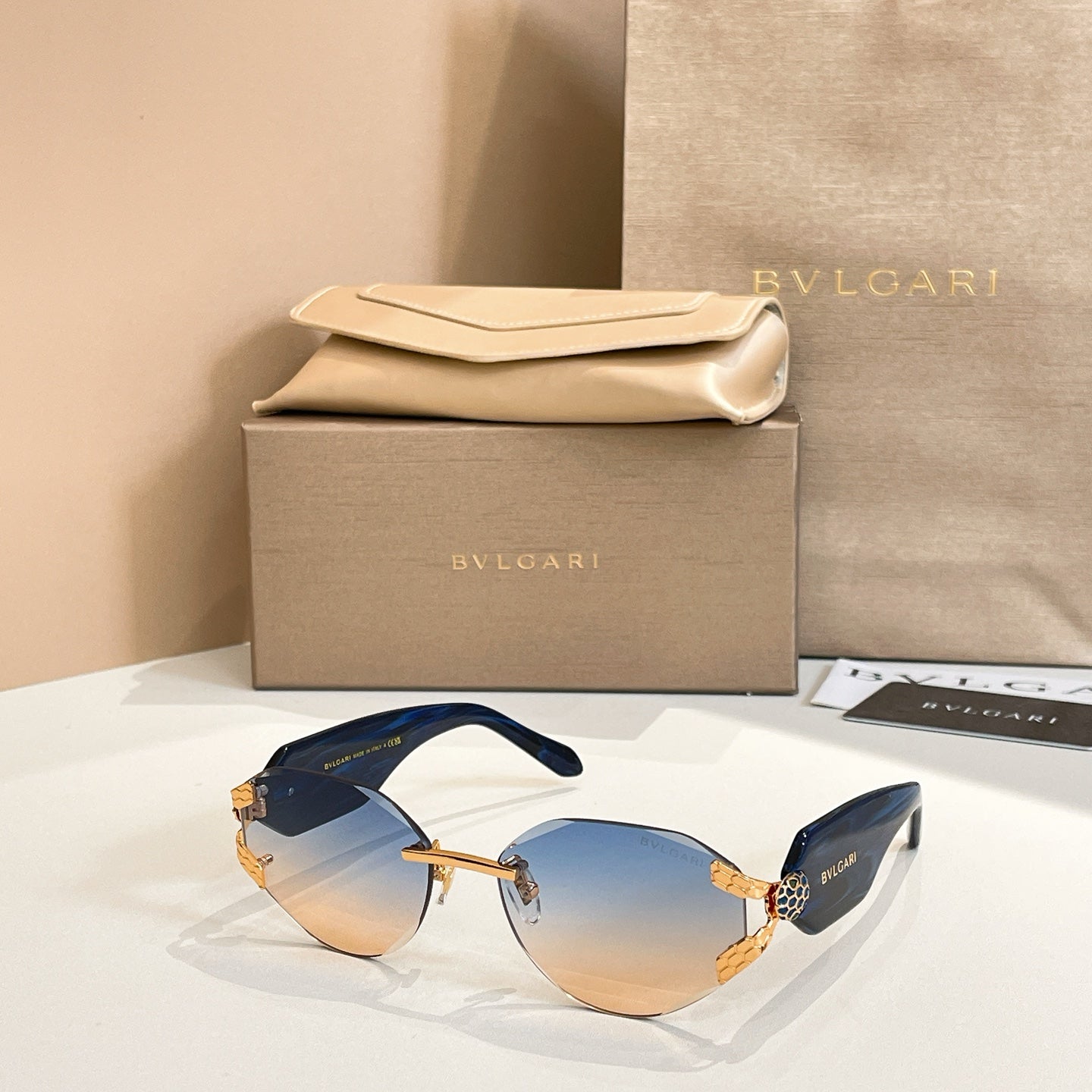 Blue-tinted gradient sunglasses with gold-tone frame and patterned temple accents