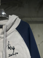 Two-tone zip-up hoodie with black signature script on front and navy sleeve