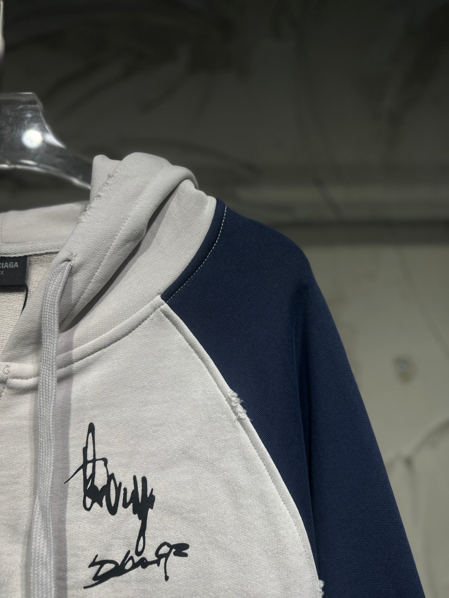 Two-tone zip-up hoodie with black signature script on front and navy sleeve