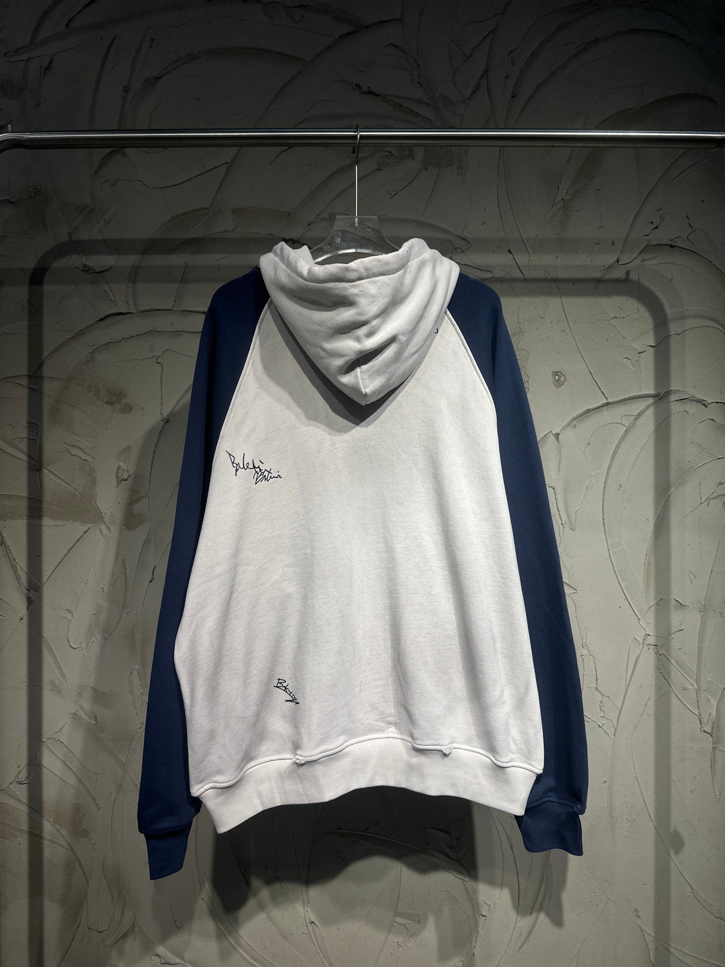 Pullover hoodie with white body, dark blue sleeves, and drawstring hood