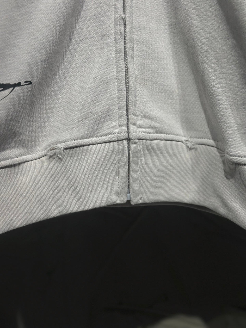 White zip-up hoodie with center zipper and stitched lower hem seam