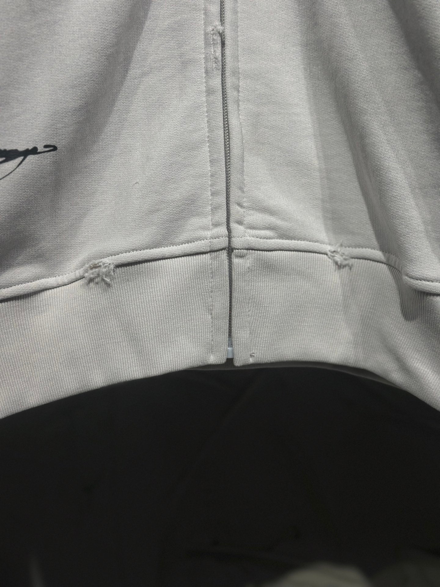 White zip-up hoodie with center zipper and stitched lower hem seam