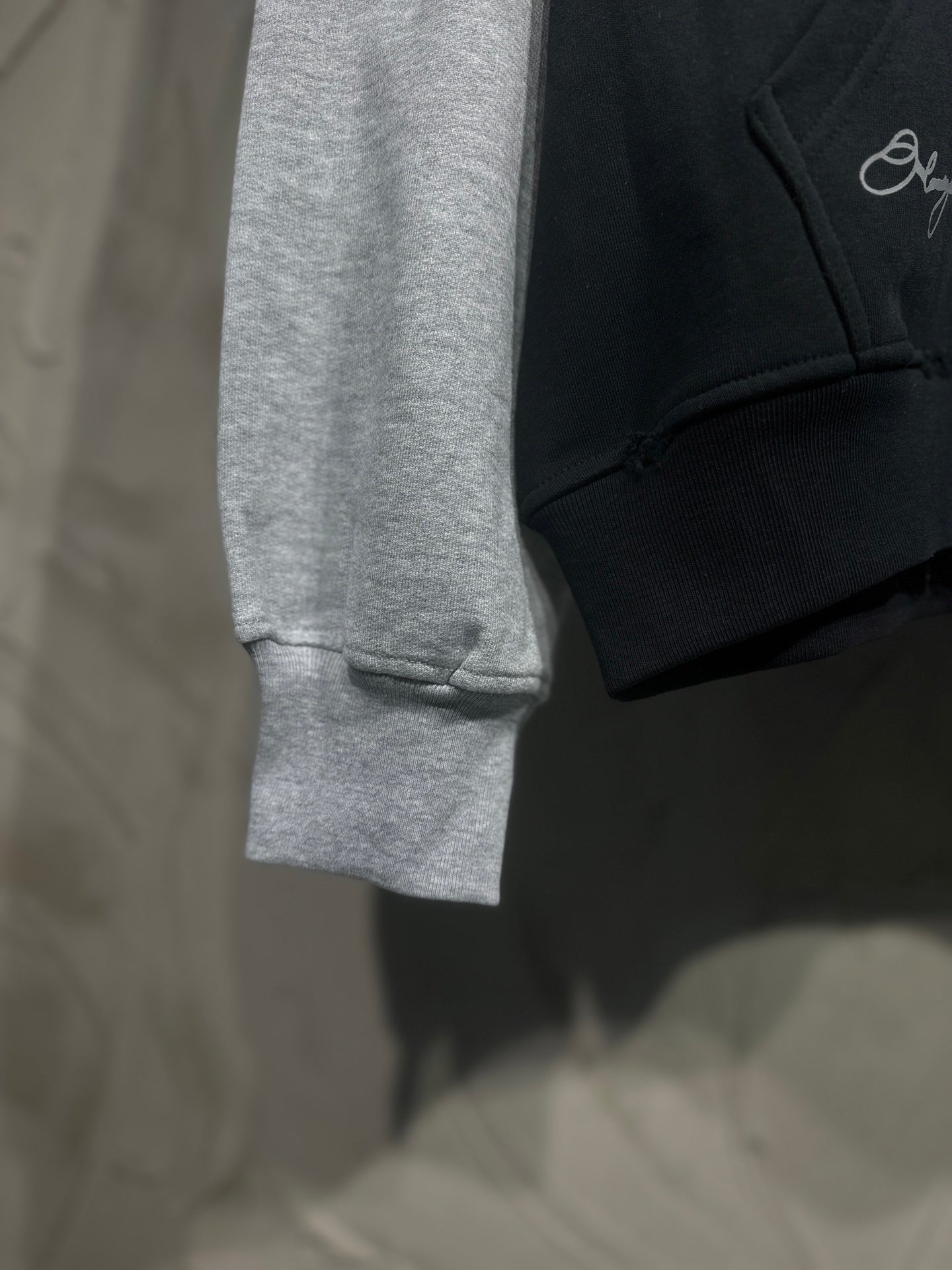 Two-tone hoodie with gray sleeves and black body; ribbed cuffs visible at hem
