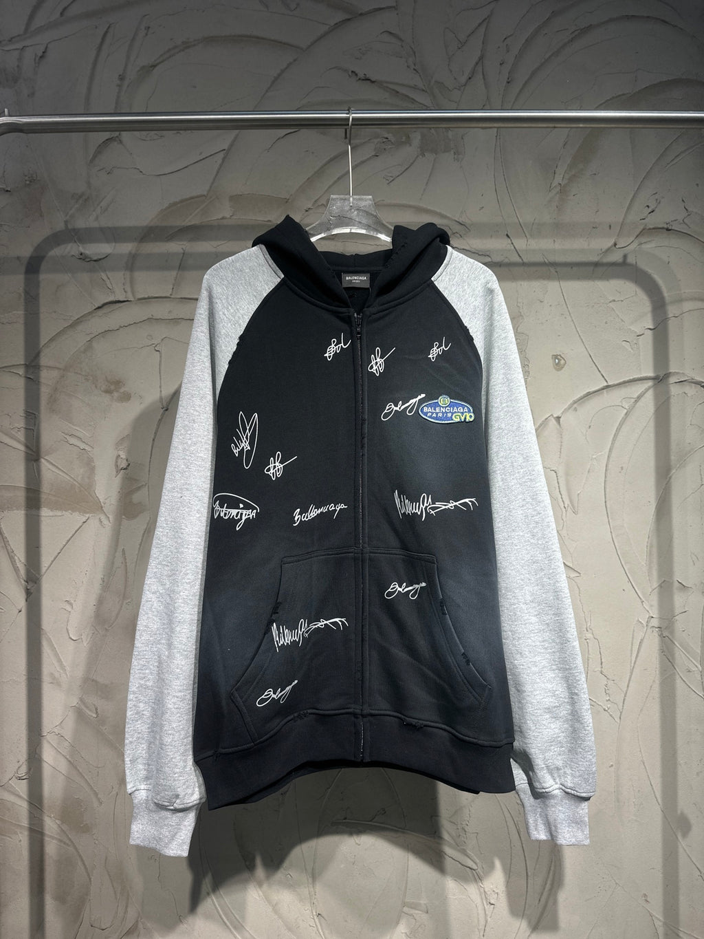Two-tone zip-up hoodie with hood; black body, gray sleeves, white script logo prints