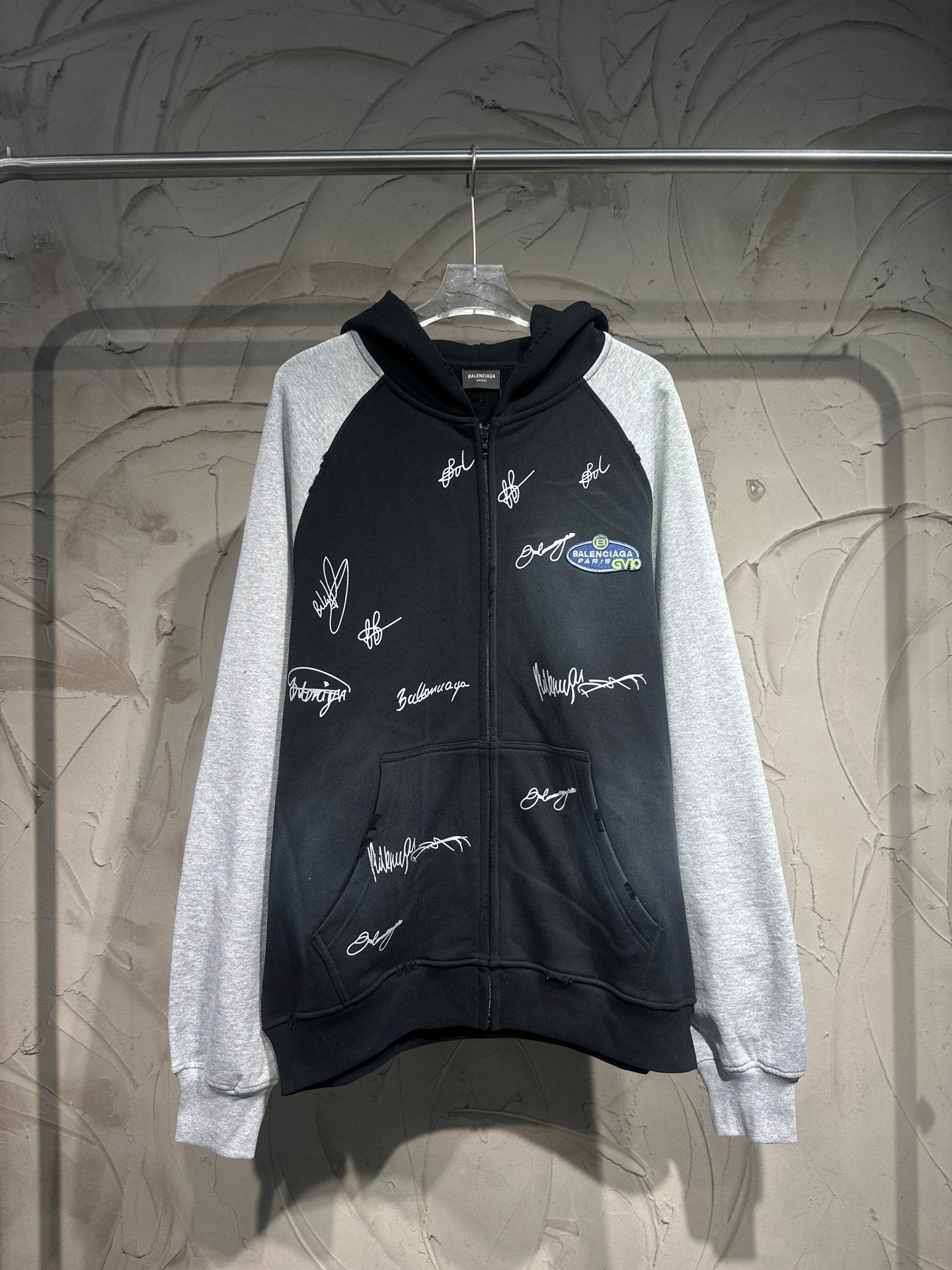 Two-tone zip-up hoodie with hood; black body, gray sleeves, white script logo prints