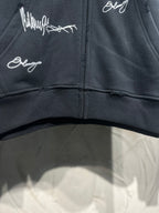 Black zip-up hoodie front; white script graphics across the chest and zipper center