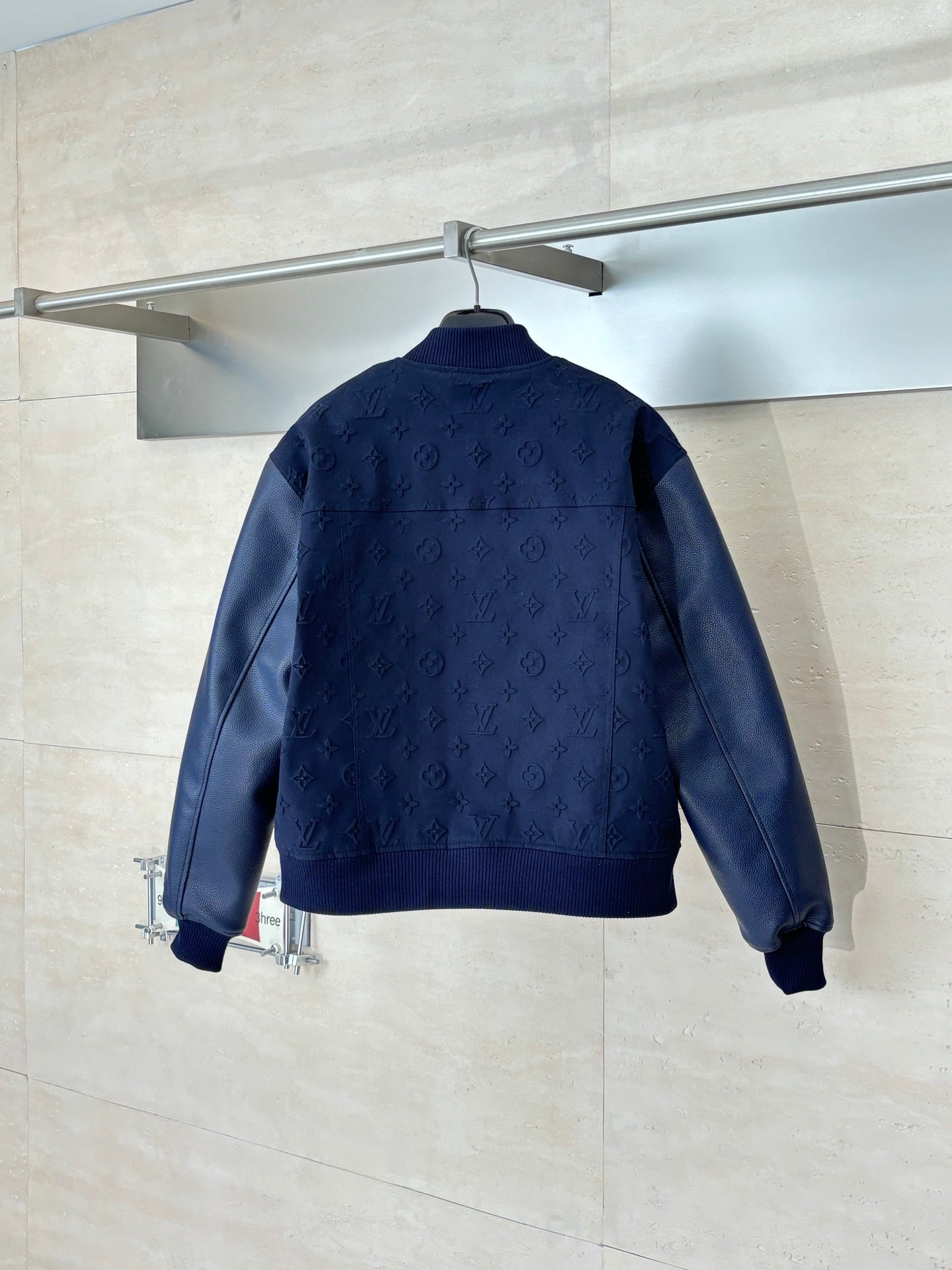 Navy monogram bomber jacket back view with ribbed collar and hem.
