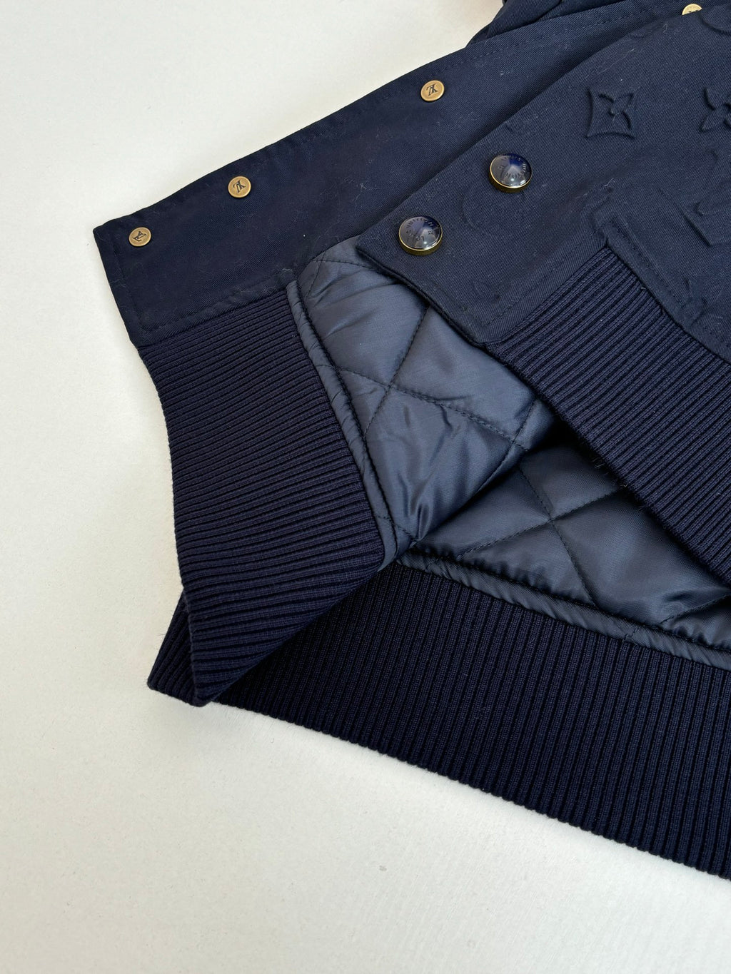 Navy bomber jacket showing quilted lining and ribbed knit waistband.