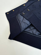 Navy bomber jacket showing quilted lining and ribbed knit waistband.