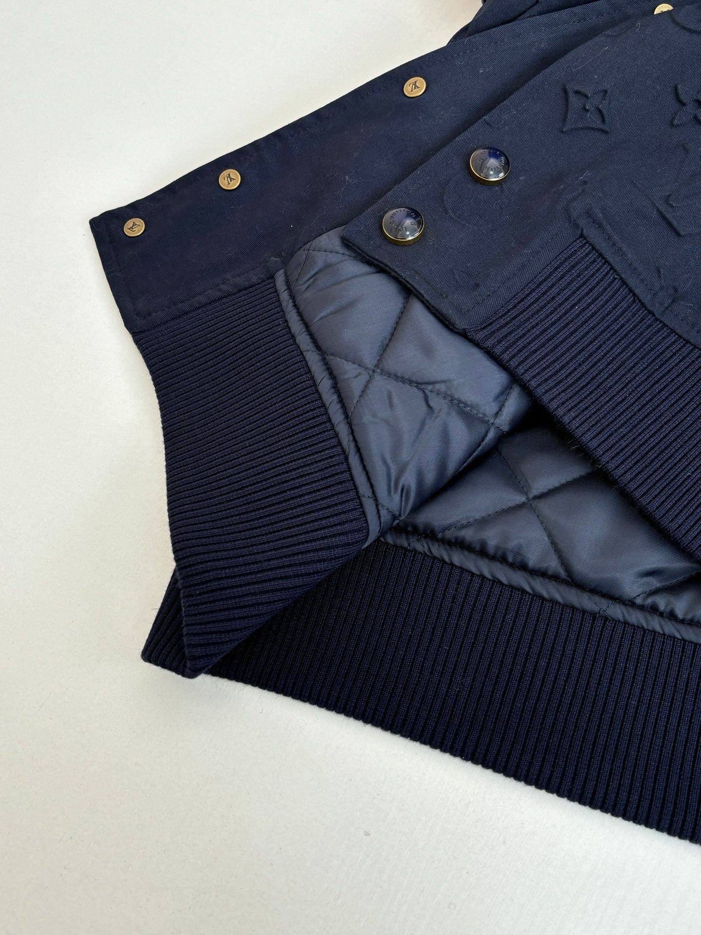 Navy bomber jacket showing quilted lining and ribbed knit waistband.