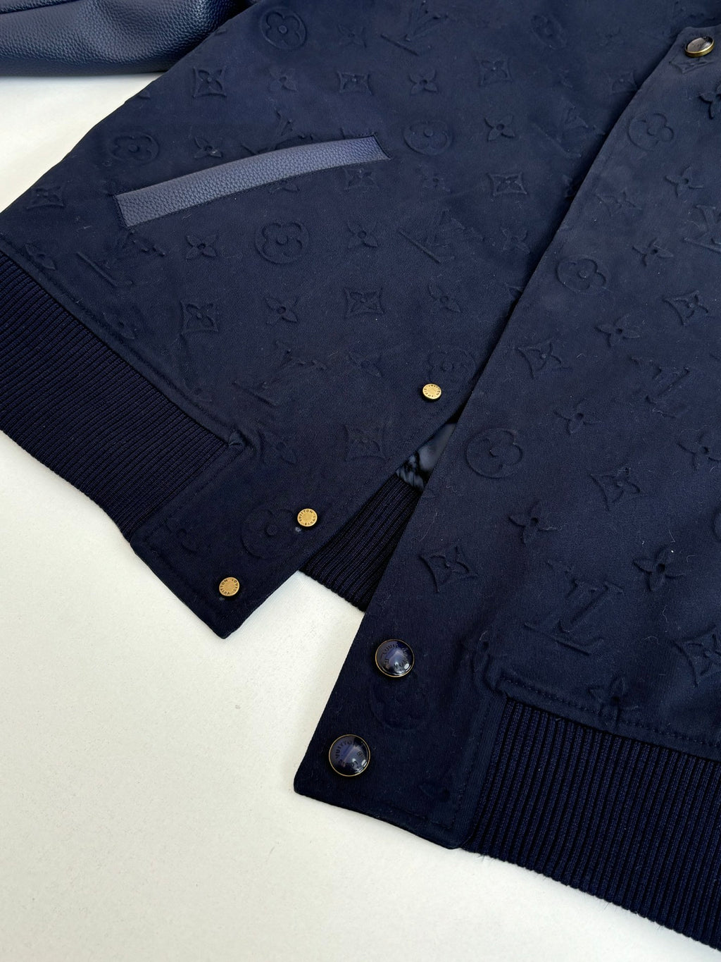 Navy monogram bomber jacket front with gold snaps and ribbed knit hem.