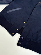 Navy monogram bomber jacket front with gold snaps and ribbed knit hem.