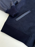 Navy bomber jacket detail: ribbed cuff and hem with snap button placket.