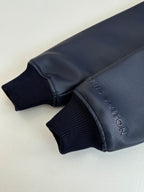 Navy ribbed sleeve cuff with embossed lettering on textured jacket trim.