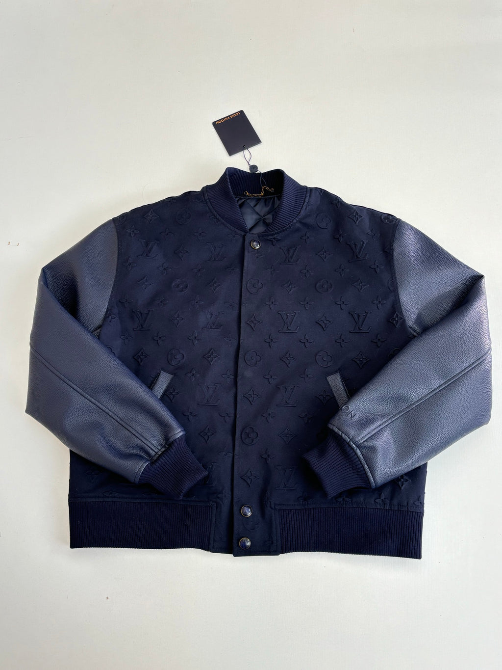 Navy zip-front bomber jacket with stand collar, monogram pattern, ribbed cuffs.