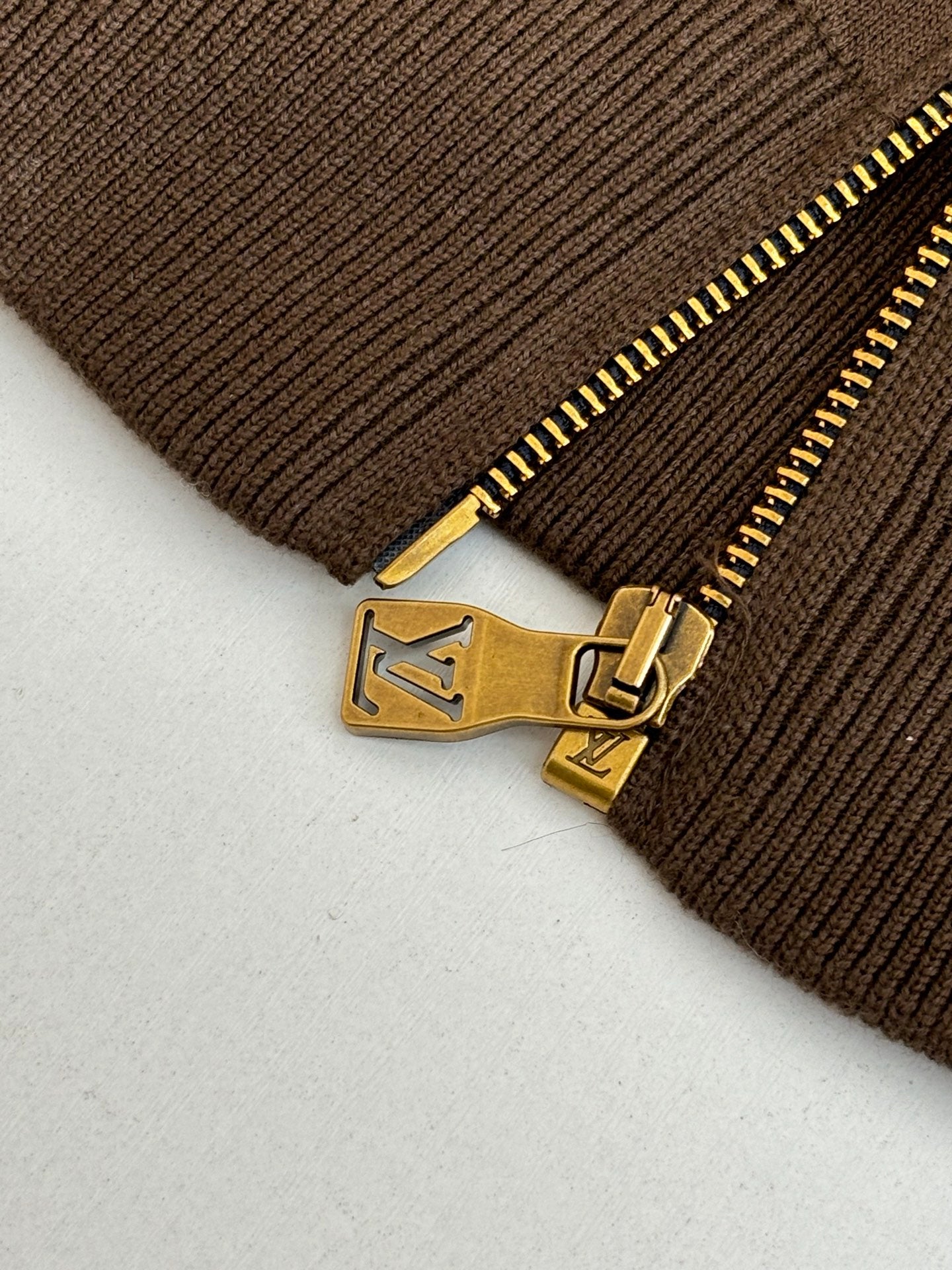 Brown ribbed cuff with gold zipper pull and engraved logo hardware