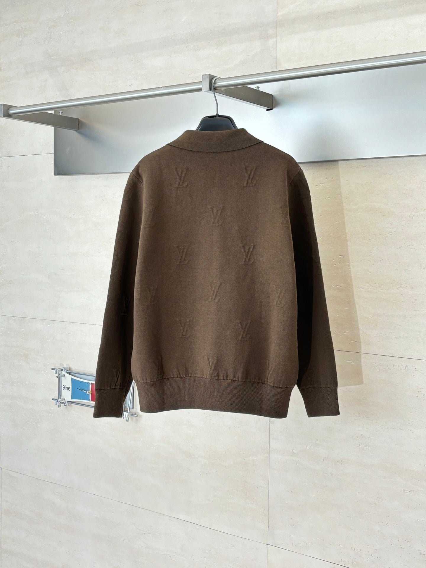 Back view of brown zip-up jacket with stand collar and gold zipper details