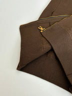 Brown jacket side seam with gold zipper track and small logo zipper pull