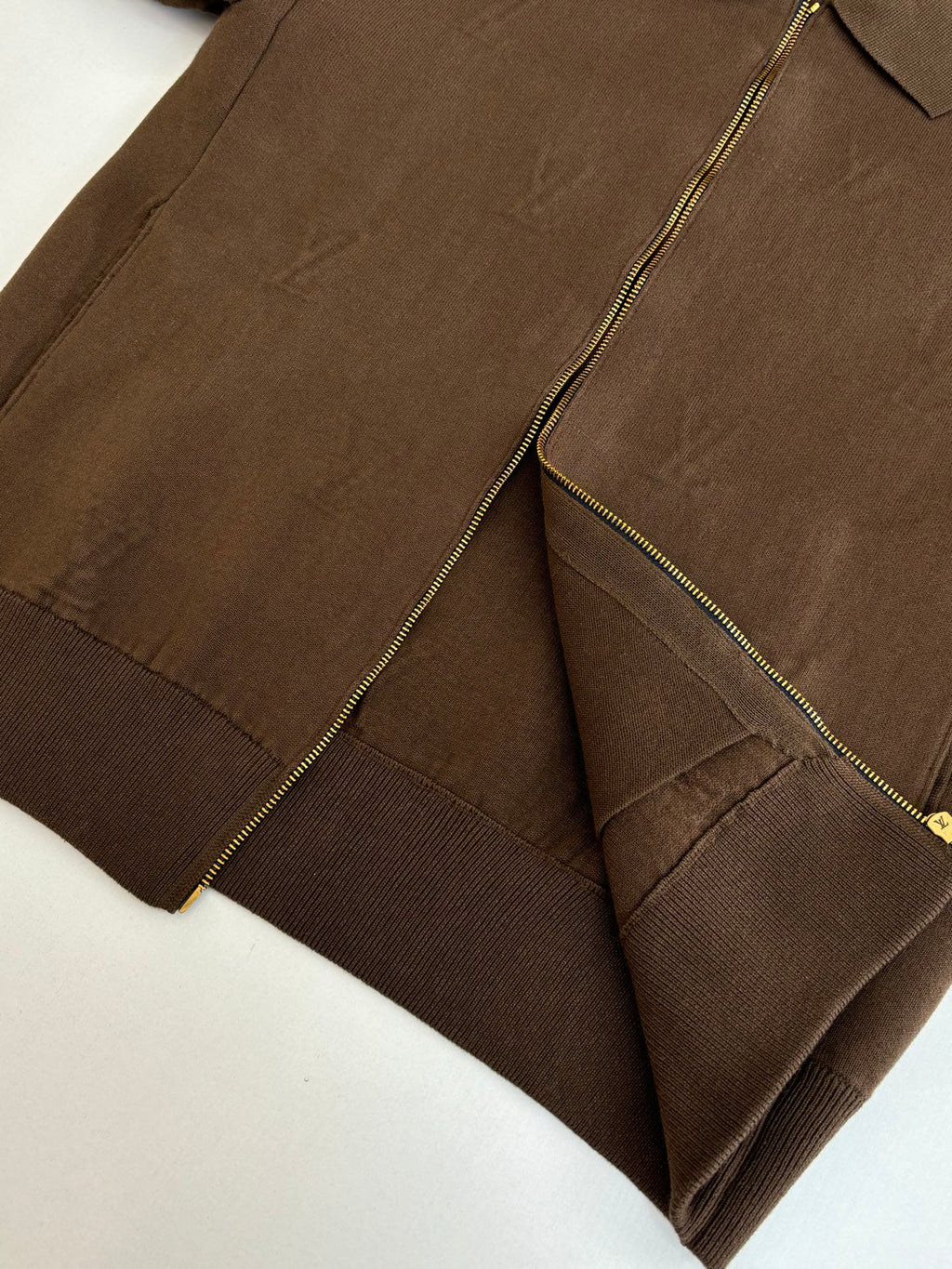 Brown jacket close-up showing front zipper, stitched panels, and ribbed hem