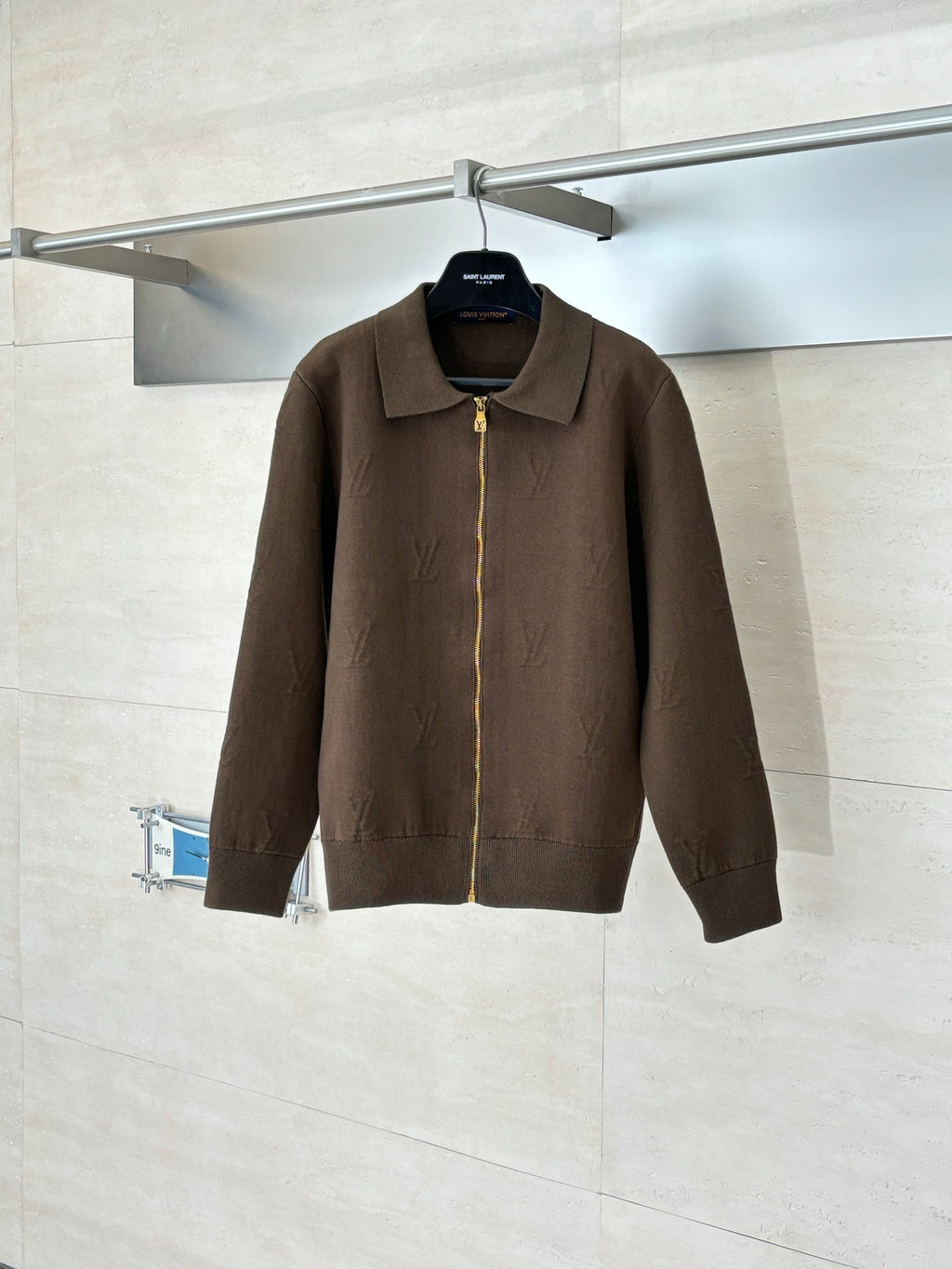 Brown zip-up jacket with stand collar and full-length gold zipper on hanger