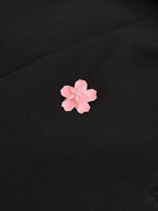 Pink flower appliqué on black blazer fabric.