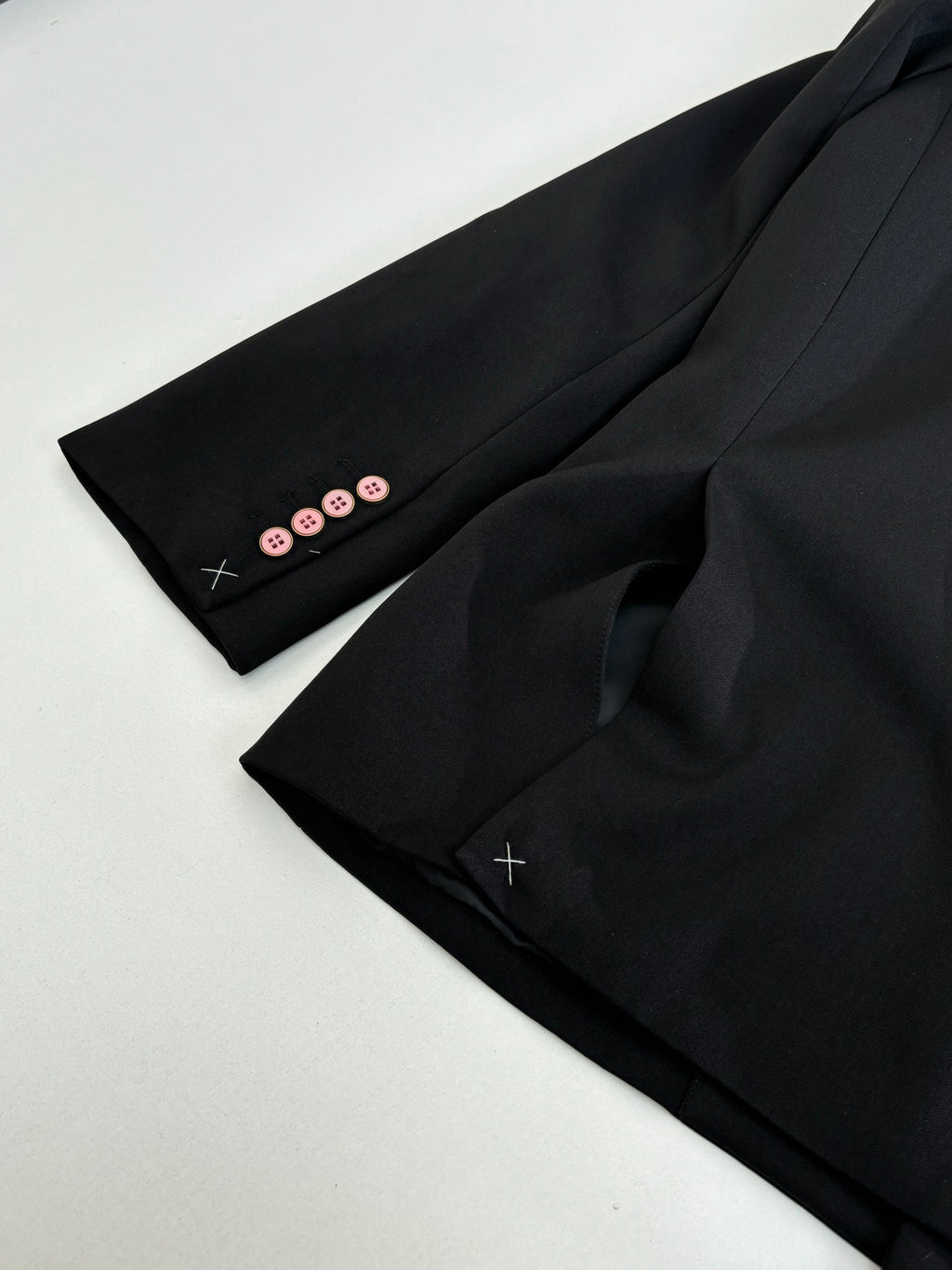 Black long blazer jacket sleeve cuff close-up with four buttons and stitched detail.
