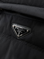 Prada Milano triangular logo patch on dark puffer jacket chest pocket