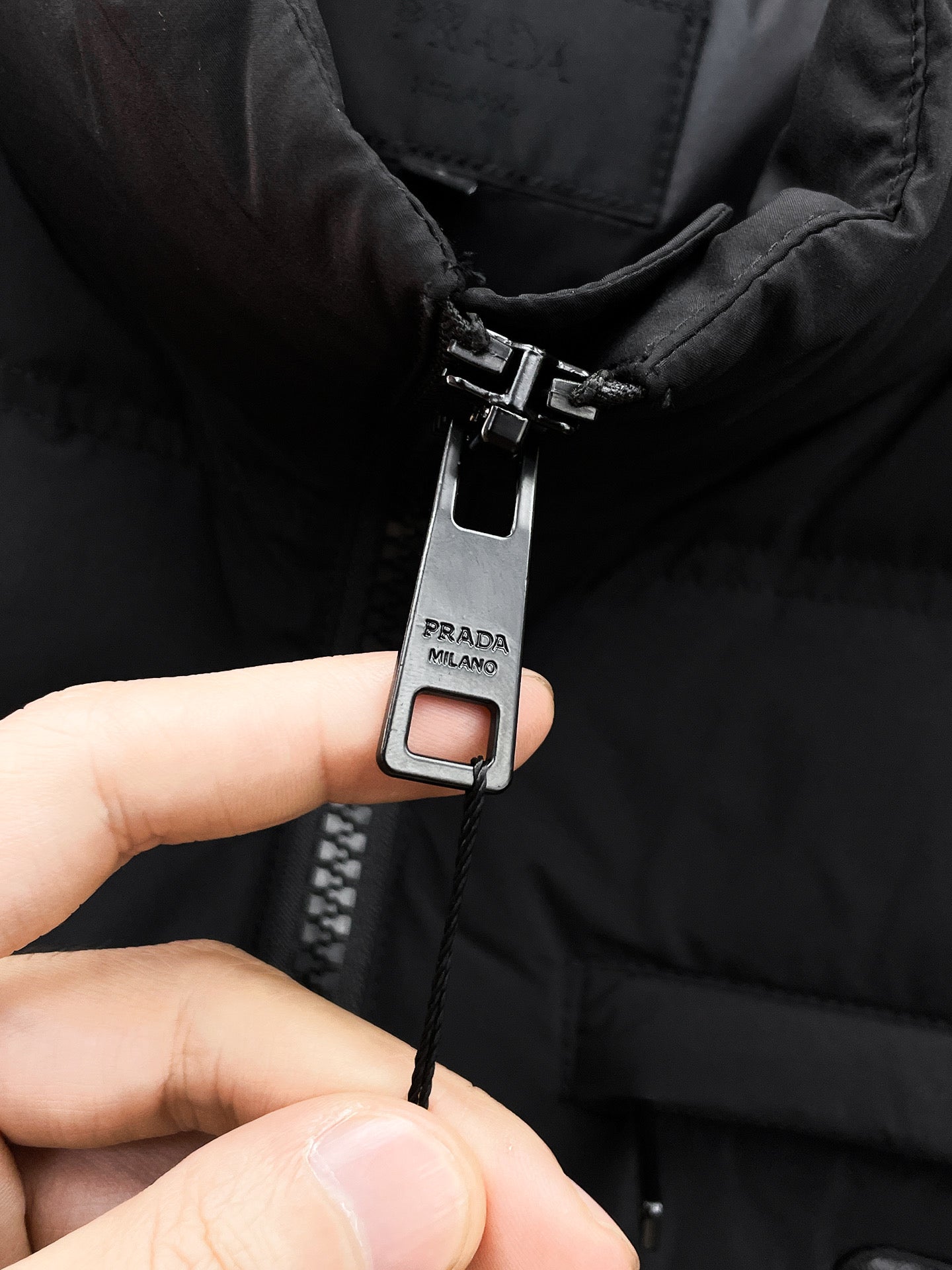 Dark puffer jacket zipper pull with Prada Milano hang tag
