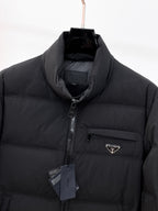 Dark long puffer jacket close-up: stand collar, front zipper, and triangular logo patch