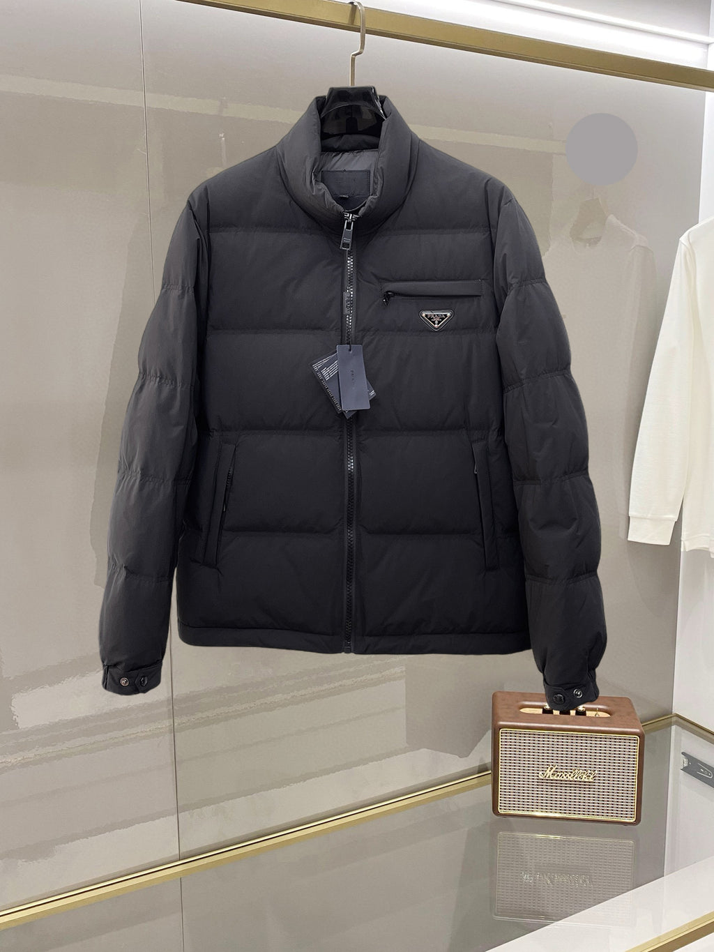 Dark long puffer jacket with front zipper and stand collar, side logo patch