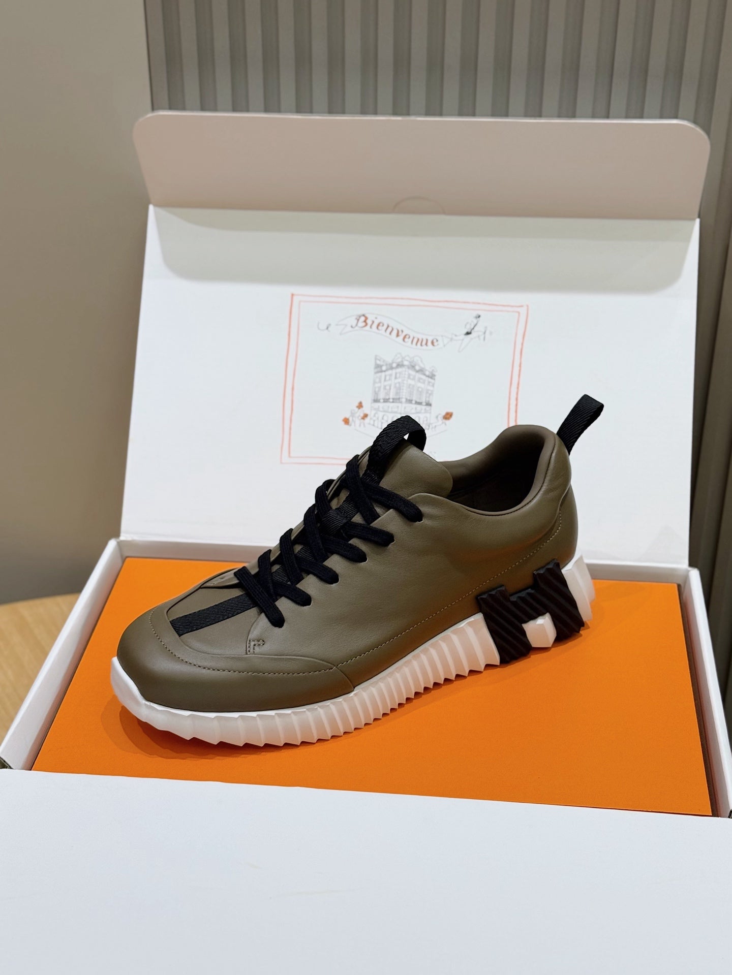 Olive low-top sneakers with navy laces, white ridged sole, and padded tongue