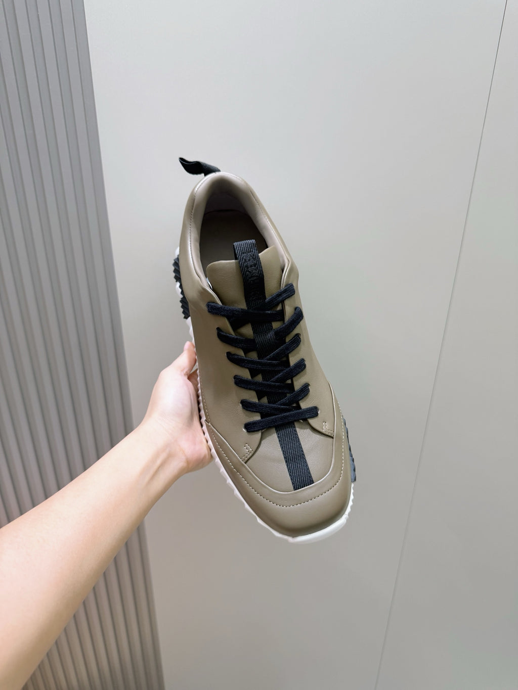 Olive sneaker with navy lace-up closure and white sole, shown from side