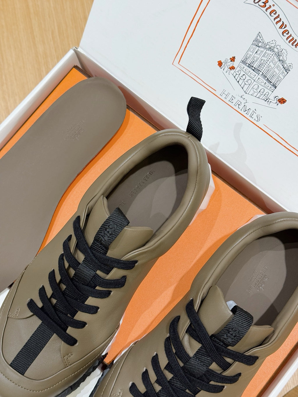 Olive sneakers in box with navy laces and white chunky soles, open toe