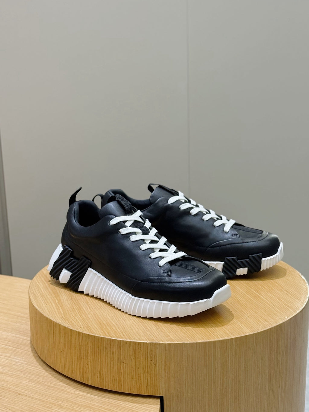 Black lace-up sneakers with white laces and textured platform sole, side view