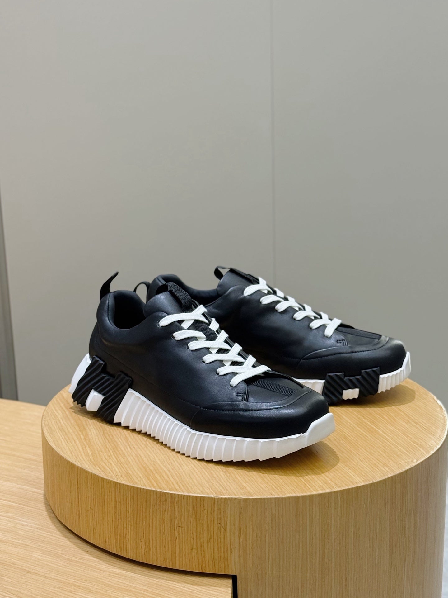 Black lace-up sneakers with white laces and textured platform sole, side view