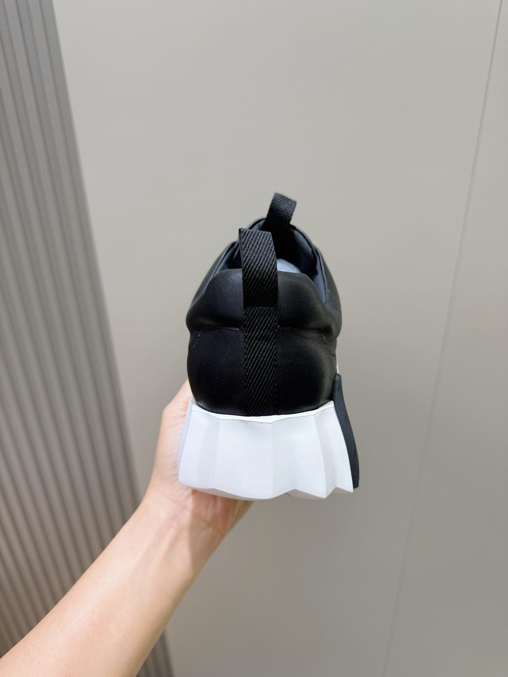 Heel view of black lace-up sneaker with white laces and white platform sole
