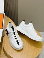 Pair of unisex white sneakers with black stripe details, on round wooden stand