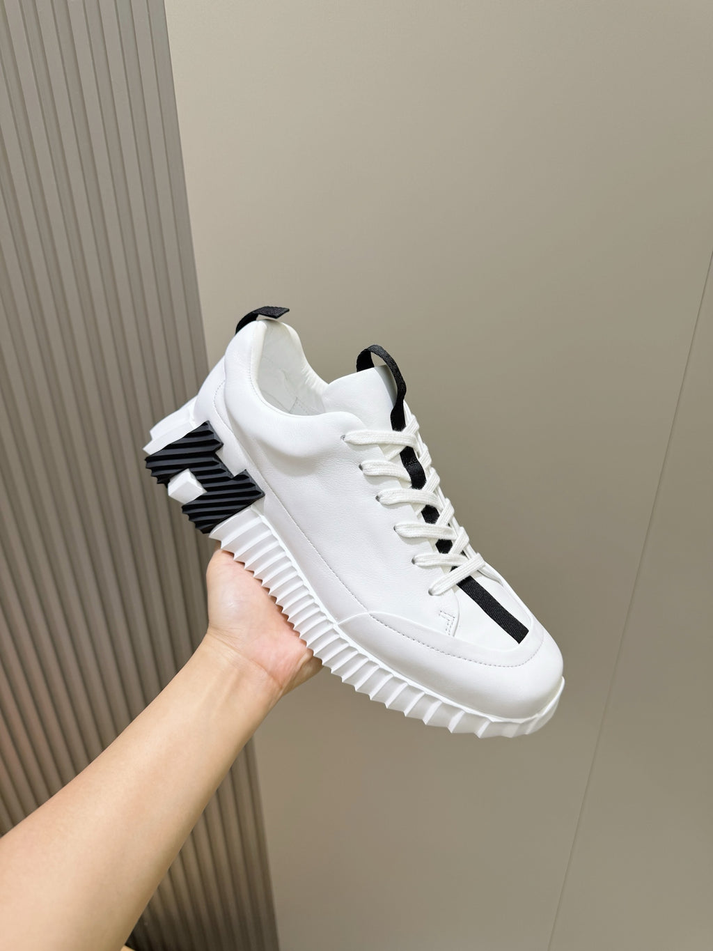 Unisex white sneakers with black logo strap on side, thick ridged sole