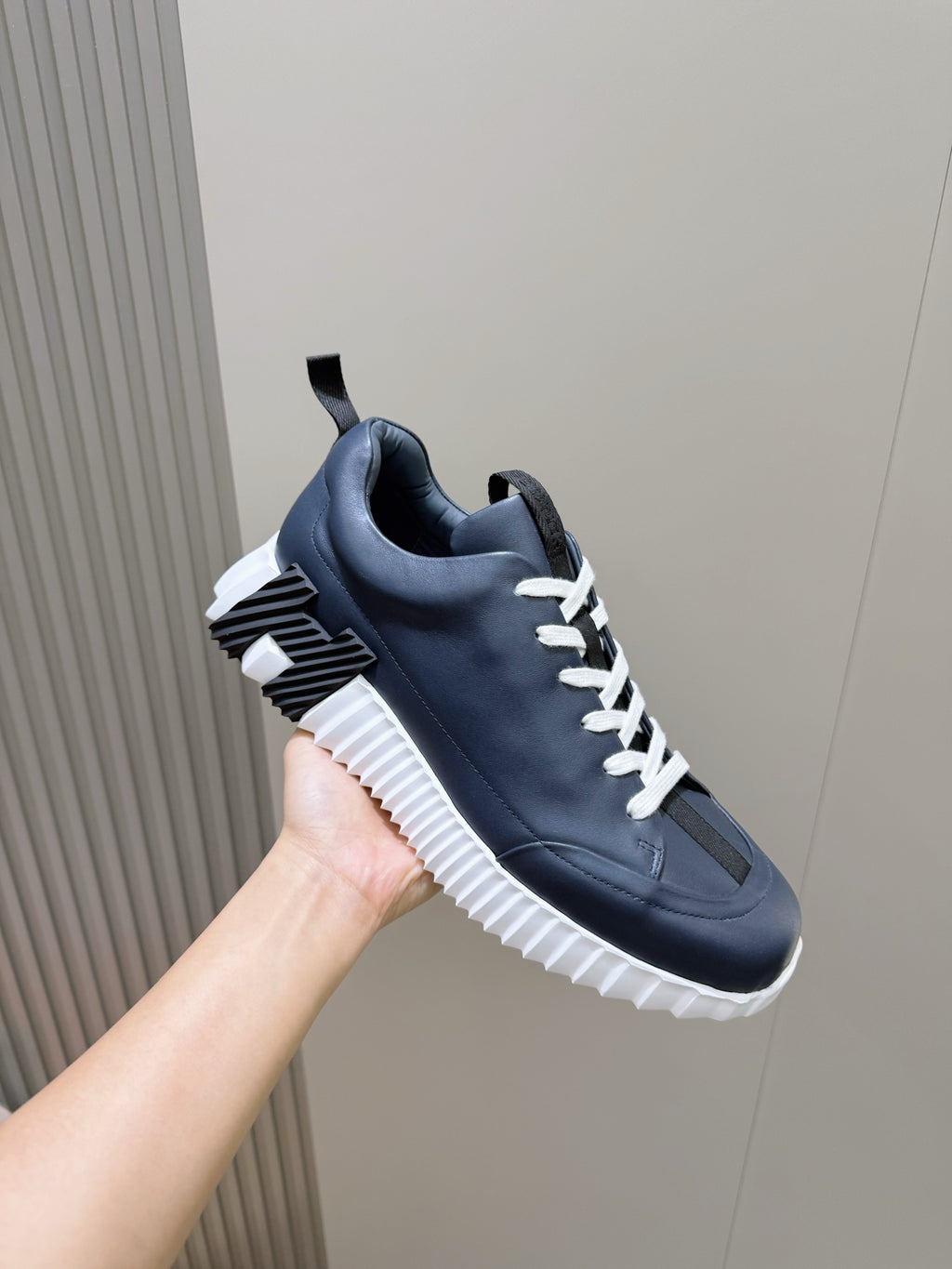 Unisex dark navy sneaker with white laces, striped sole detail, and side panel