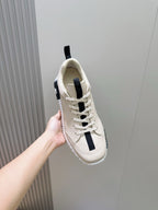 Hermes unisex sneaker close side view, light cream leather with black stripe accents
