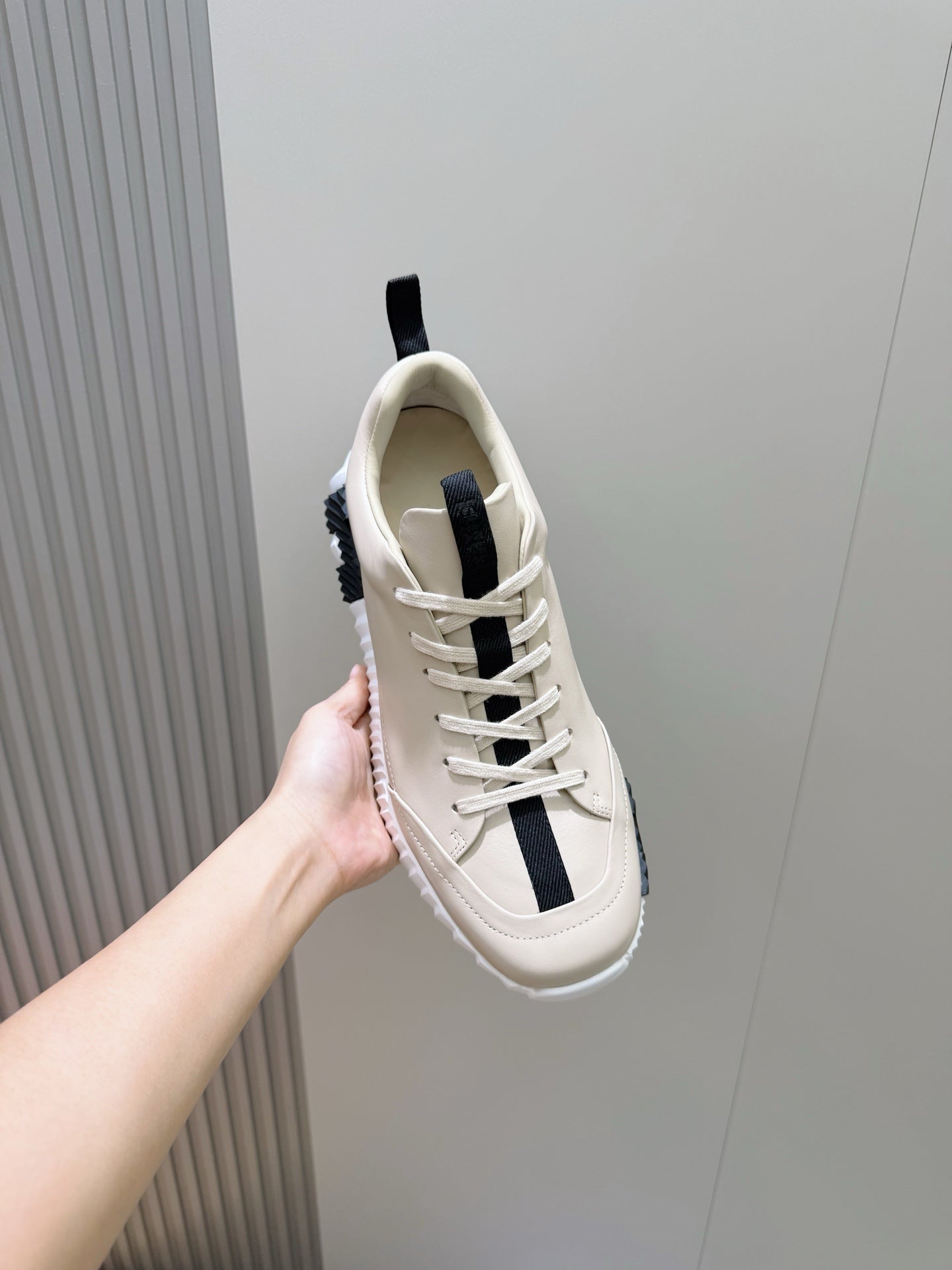 Hermes unisex sneaker close side view, light cream leather with black stripe accents