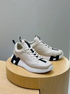 Hermes unisex sneakers on a stand, light cream leather with black side detailing