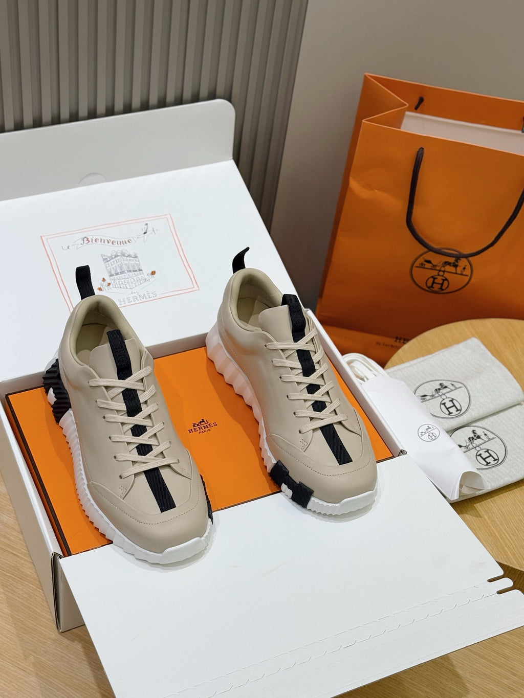 Unisex luxury sneakers by Hermes, cream leather with navy side stripe and lace-up