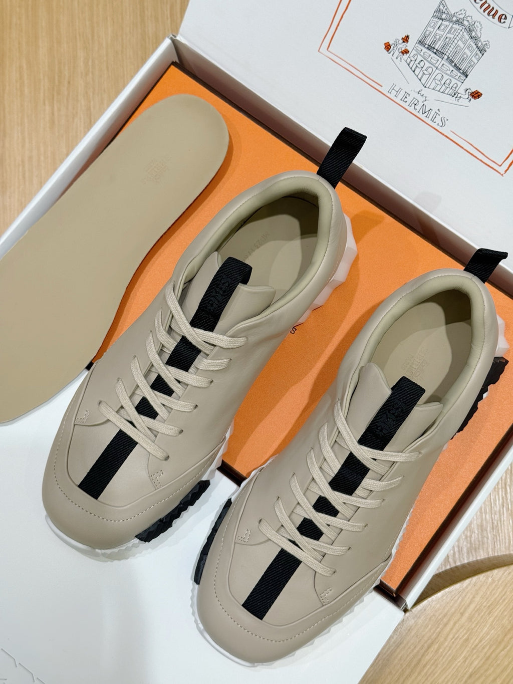 Unisex luxury sneakers by Hermes, cream leather with navy side stripes, lace-up pair