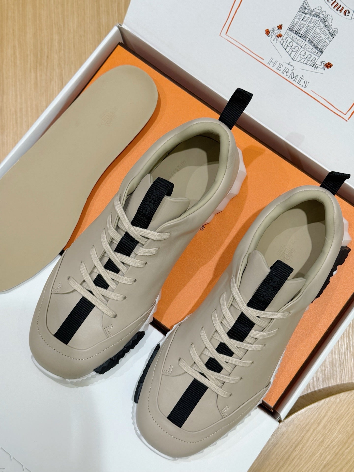Unisex luxury sneakers by Hermes, cream leather with navy side stripes, lace-up pair