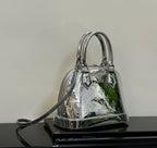 Louis Vuitton monogram handbag with top handles and crossbody strap, reflective silver finish