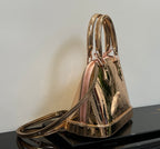 Louis Vuitton bag shown from side with dual top handles and gold metallic sheen, monogram.